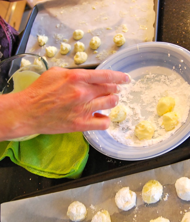 Rolling the champagne truffles first in white chocolate couverture, then in icing sugar.